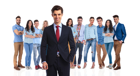 smiling team leader standing with his casual team behind on white background. He is looking relaxed while having a hand in pocket.の写真素材