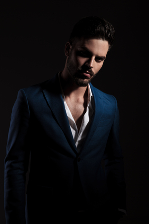 sexy smart casual man with undone shirt standing on a black, dark, backgroundの写真素材