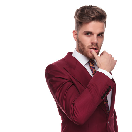 portrait of seductive elegant man wiping his lips with thumb while standing on white backgroundの写真素材