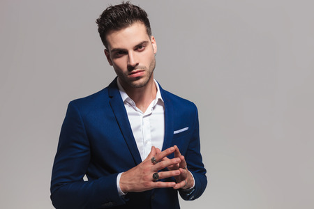 sexy young legant man holding palms together like a prayer on grey backgroundの写真素材