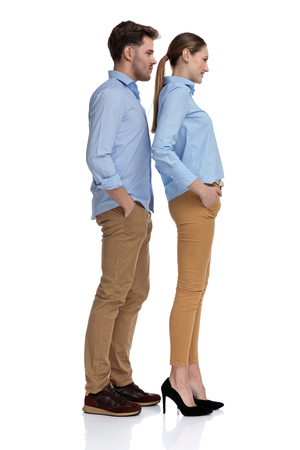 young casual couple with hands in pockets, waits in line , full body picture on white backgroundの写真素材