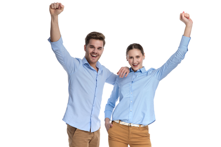 hapy young winning couple standing with hands in the air on white backgroundの写真素材