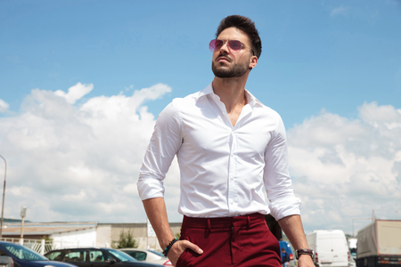 attractive man wearing sunglasses walking holding his head high in parking lotの写真素材
