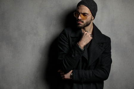 Well dressed man looking away with his hands crossed in front of a grey wallの写真素材