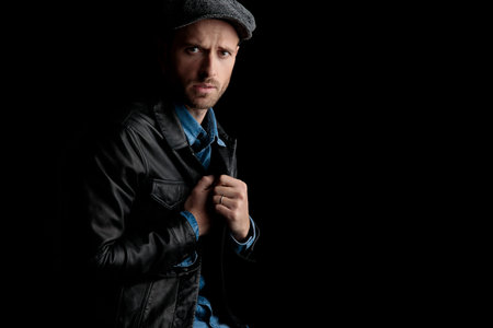 seated frown man adjusting his collar on his black leather jacket