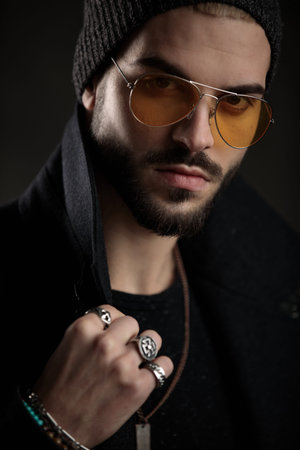 hipster model guy wearing beanie and orange sunglasses adjusting his coat collar