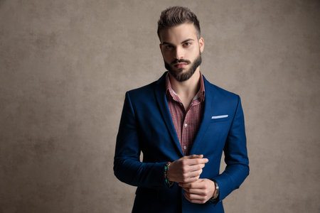 portrait of a sexy formal business man wearing a navy suit and holding hands while looking at camera...
