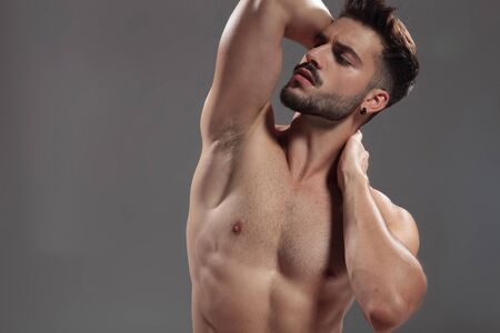 close up of seductive young model touching neck and looking to side on grey background, portraitの写真素材