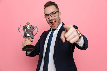 smiling young businessman in suit wearing glasses and framing, standing on pink backgroundの写真素材