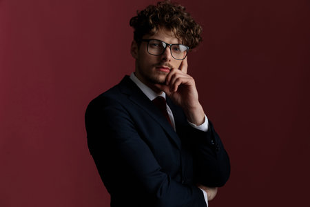cool sexy businessman with attitude folding his hands and touching his chin in a fashion pose on...