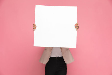 businesswoman showing a blank board at the camera on pink background