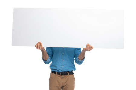 casual man hiding his face behind a wide billboard against white backgroundの写真素材