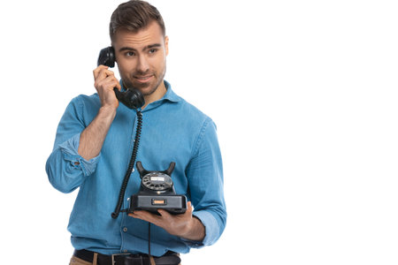 casual young man listening to someone on the telephone then thinking what response to give against...