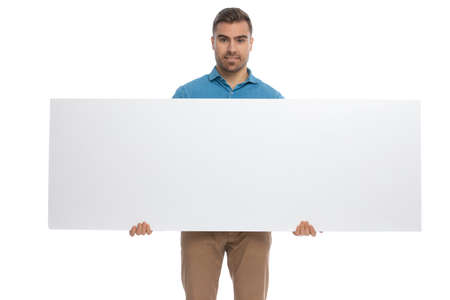 sexy casual man holding a wide billboard in his hands and smiling against white backgroundの写真素材
