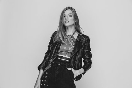 cool casual model in leather jacket holding hands in pockets, confidently standing in a fashion pose on black and white backround in studioの写真素材