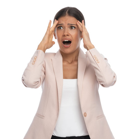 disturbed young female in pink jacket holding hands to forehead, screaming, having a headache and...