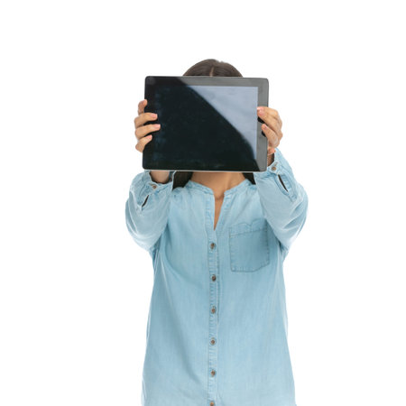 attractive casual woman hiding her face behind her tablet against white background
