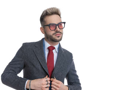 portrait of an attractive businessman arranging his coat and looking away against white backgroundの写真素材
