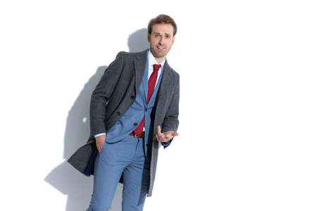attractive businessman gesturing a what's up sign, sticking one hand in pocket on white backgroundの写真素材
