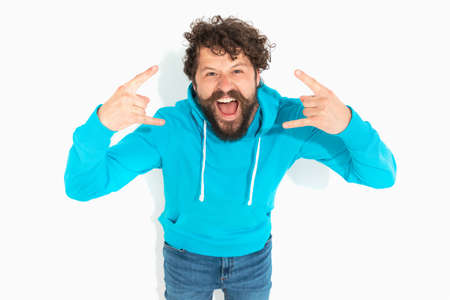 attractive casual man feeling excited, gesturing a rock sign on white backgroundの写真素材