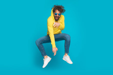 funnt casual man with retro glasses, long beard and moustache jumping in the air and having fun...