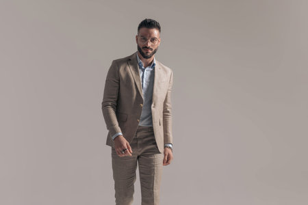 sexy businessman walking towards the camera and wearing a cool suit and eyeglasses