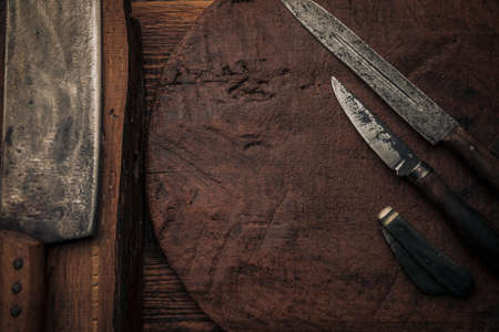 little old penknife next to rusty old knives and a cleaver on top of old wooden cutting boards with copy spaceの写真素材