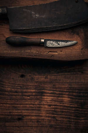 aged cutting utensils , little knife and cleaver, on a piece onf old wood with copy space for your messageの写真素材