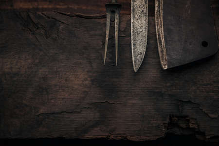 closeup of  old fork, knife and cleaver tips on a rustic  wooden boardの写真素材