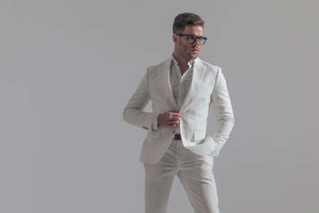 attractive businessman looking away, holding one hand in pocket and the other on his buttonの写真素材