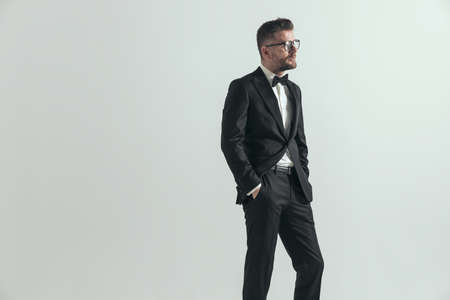 businessman in black tuxedo is looking to side with his hands in pockets and wearing eyeglassesの写真素材