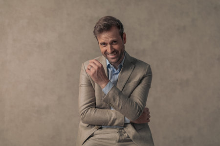 sexy businessman with a seductive smile on his face is crossing his arms and posing against...