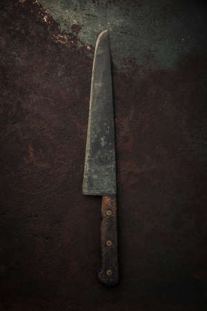 vintage carbon steel kitchen knife with wooden handle on top of rusty metallic background, table topの写真素材