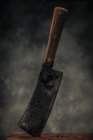 concept of cooking illustrated by carbon steel butcher on chopping board in front of dark texture...