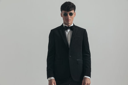 Portrait of attractive businessman posing with style, standing, wearing a black tuxedo and...