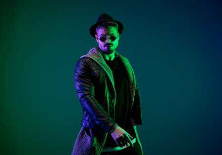 Portrait of handsome casual man posing with hands hanging loosely in a play of colorful lightsの写真素材