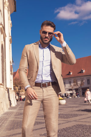 Portrait of handsome businessman arranging sunglasses and posing, wearing sunglasses outdoor, in the old medieval townの写真素材