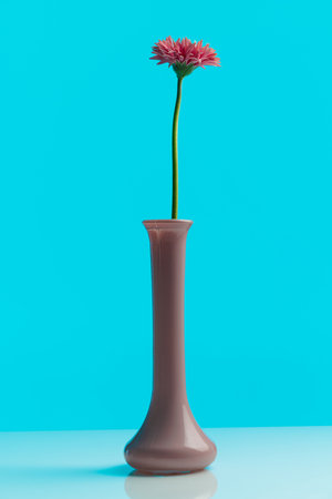 Nature themed picture of pretty pink gerbera daisy standing in a pot against blue backgroundの写真素材