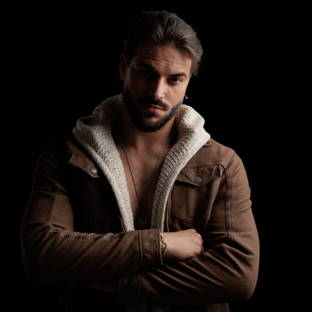 portrait of happy cool man with beard in wool cardigan and jacket crossing arms and smiling in front...