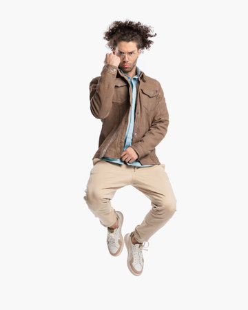 sexy young man with fist up jumping in the air and celebrating victory in front of white background in studioの写真素材