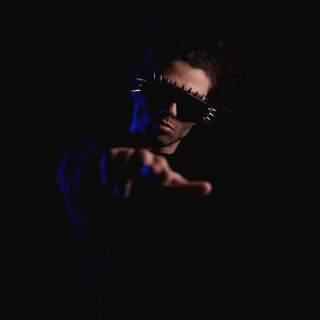 portrait of fashion cool man with cool glasses pointing fingers to camera and being confident while...