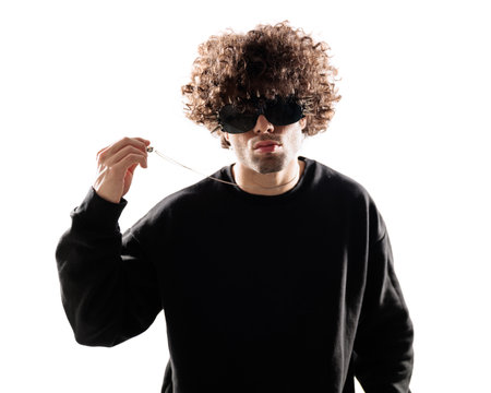 handsome man with curly hair wearing glasses, holding necklace and posing in a cool way on white backgroundの写真素材