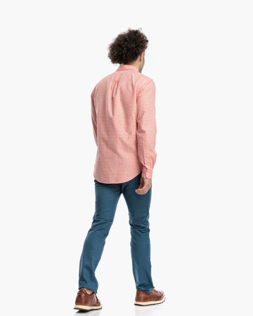 rear view of curly hair guy in plaid shirt with sneakers walking in front of white background in studioの写真素材