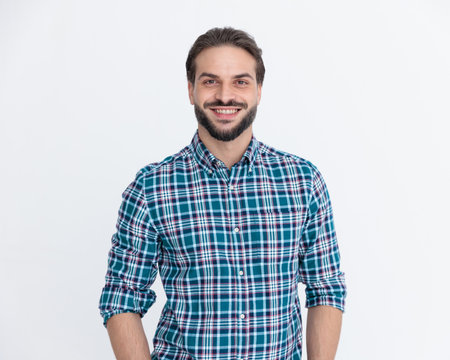 happy young guy in casul plaid shirt looking forward and smiling in front of grey backgroundの写真素材