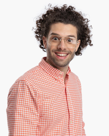 portrait of happy casual man with curly hair smiling and looking forward in front of white background in studioの写真素材