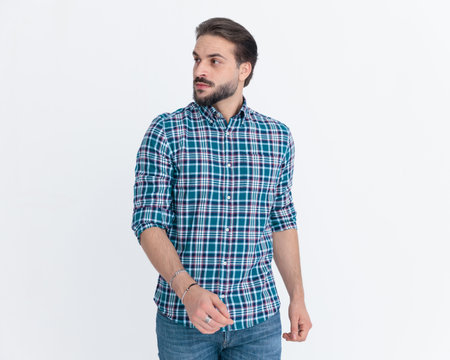 sexy young casual guy looking to side and walking in front of grey background in studioの写真素材