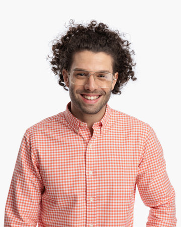 enthusiastic young man with curly hair and glasses being happy and laughing in front of white background in studioの写真素材