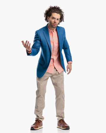 smart casual guy with glasses and curly hair gesturing and questioning while standing in front of white background in studioの写真素材