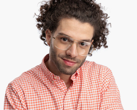 portrait of handsome young man with curly hair and glasses smiling in front of white background in studioの写真素材