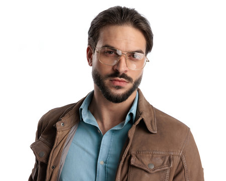 attractive young man with glasses looking forward and posing in front of white backgroundの写真素材